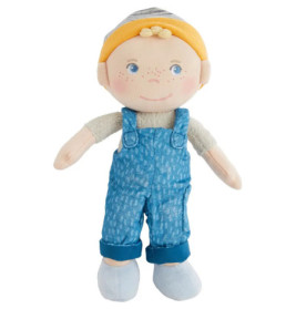 Stoffpuppe mit gelben Haaren, blauer Latzhose, gestreifter Mütze, blauen Schuhen und fröhlichem Gesicht.