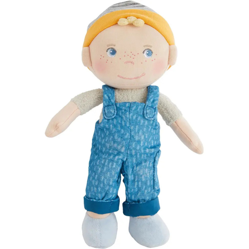 Stoffpuppe mit gelben Haaren, blauer Latzhose, gestreifter Mütze, blauen Schuhen und fröhlichem Gesicht.