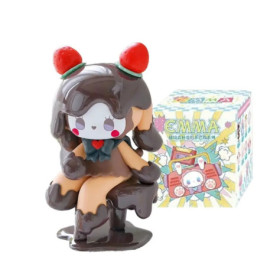 Schokoladen-Figur mit Erdbeerhaaren und rotem Herz sitzt neben einer bunten Box.