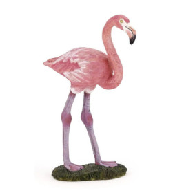 Ein pinkes Flamingofigürchen steht auf grünem Sockel, nach rechts gewandt vor weißem Hintergrund.