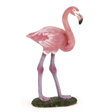 Ein pinkes Flamingofigürchen steht auf grünem Sockel, nach rechts gewandt vor weißem Hintergrund.