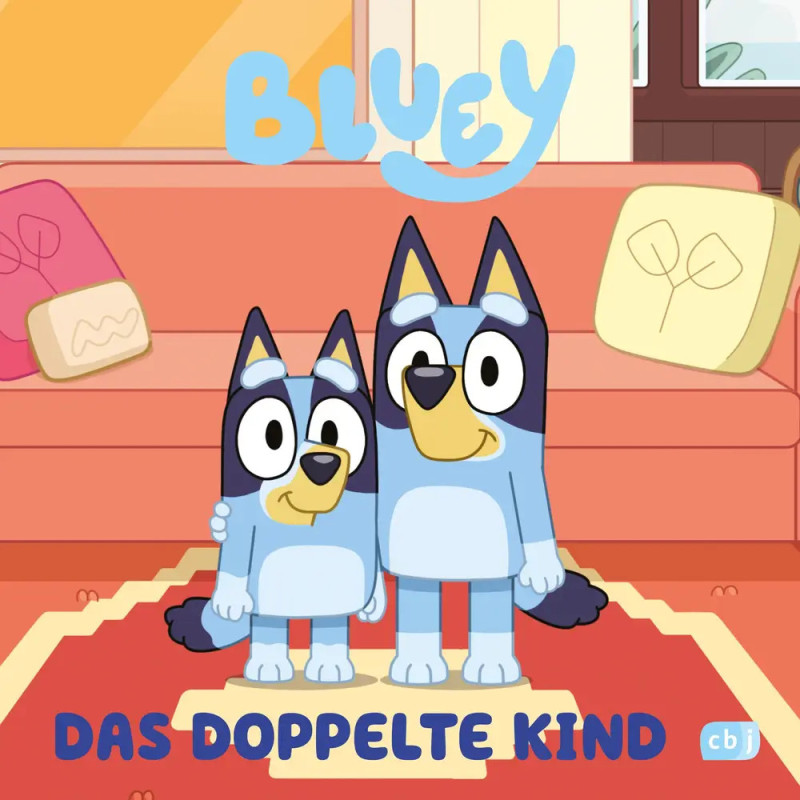 Bluey und ein weiterer Blue Heeler stehen lächelnd im Wohnzimmer. Text: Bluey Das Doppelte Kind.
