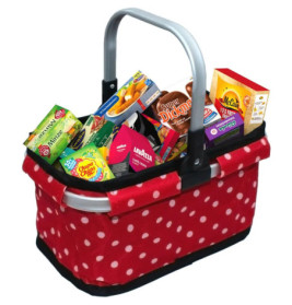 Roter Einkaufskorb mit weißen Punkten, gefüllt mit verpackten Lebensmitteln und Snacks.