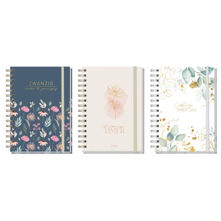 Drei spiralgebundene Planer mit floralen Kappen in Blau, Weiß und Pastell stehen aufrecht nebeneinander.