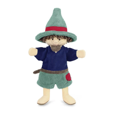 Eine Plüschpuppe steht aufrecht, trägt grünen Hut, blaues Shirt und grüne Shorts mit rotem Aufnäher.